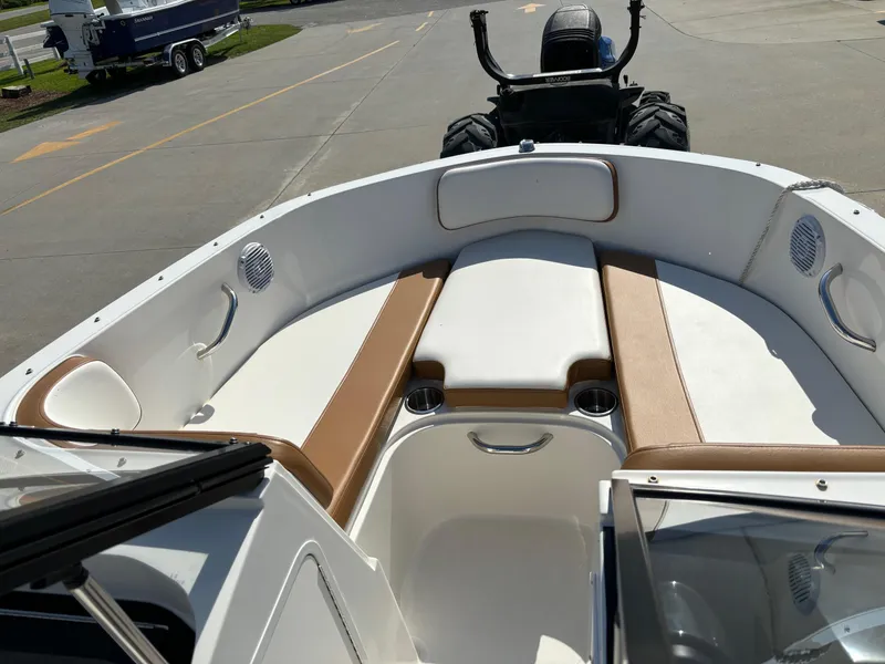 Slide: The Image of 2021 Bayliner VR4 Bowrider OB interior with tan and white seating, parked on pavement. - 11