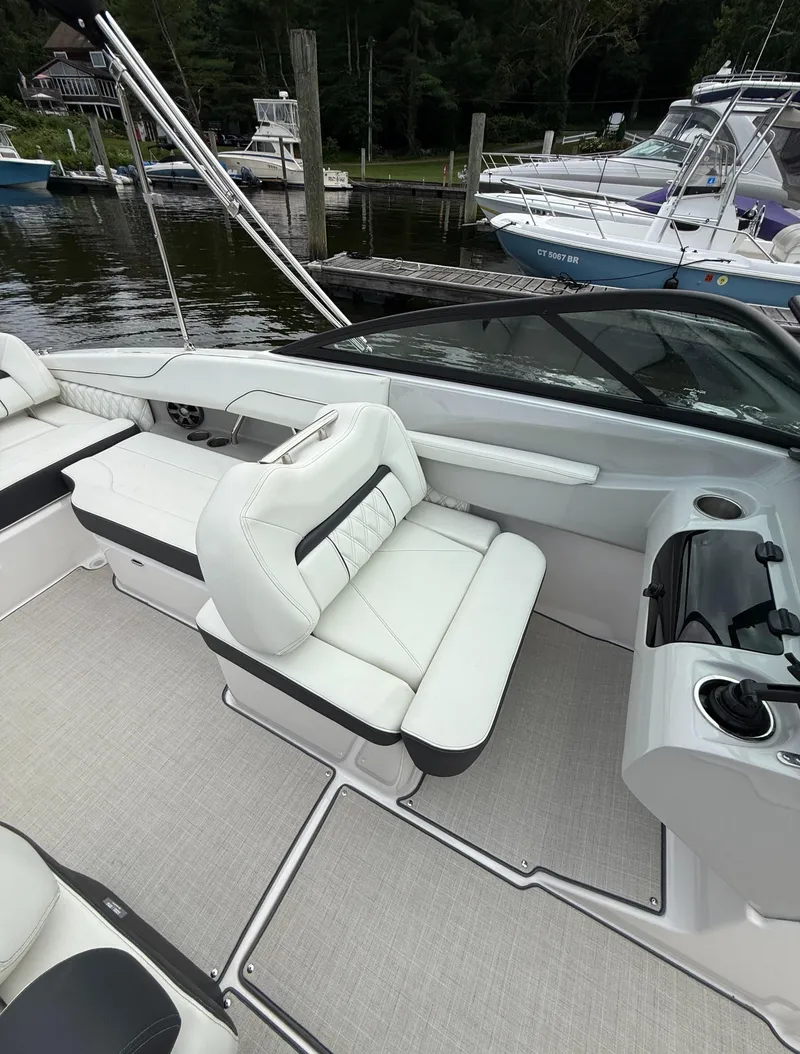 Slide: The Image of 2022 Regal LX2 boat interior with white seating and sleek design at a marina. - 13