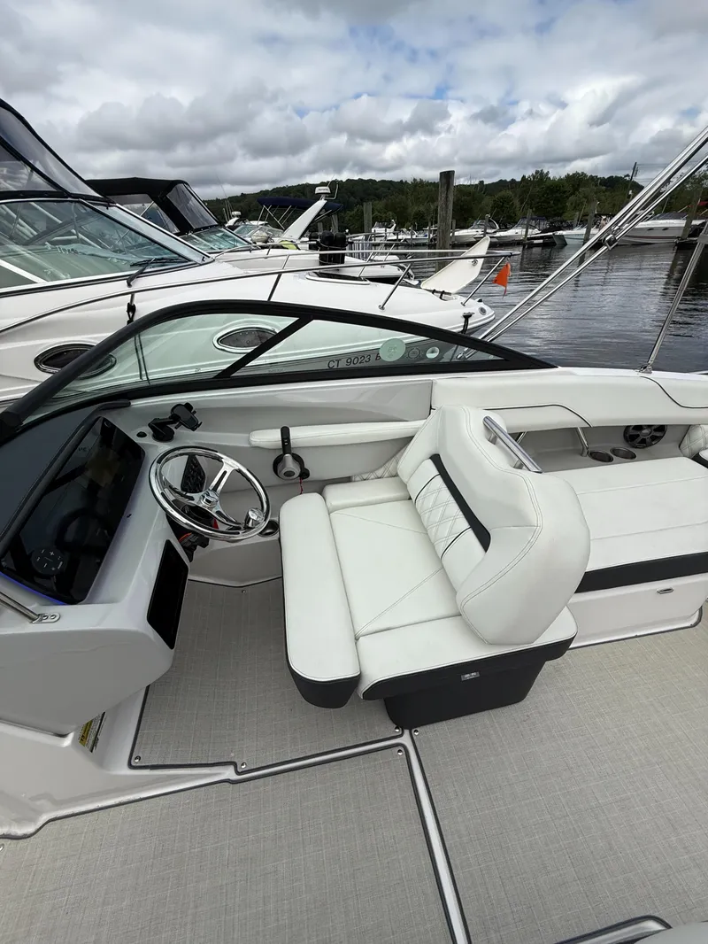 Slide: The Image of 2022 Regal LX2 boat interior with white seating and steering wheel at a marina. - 14