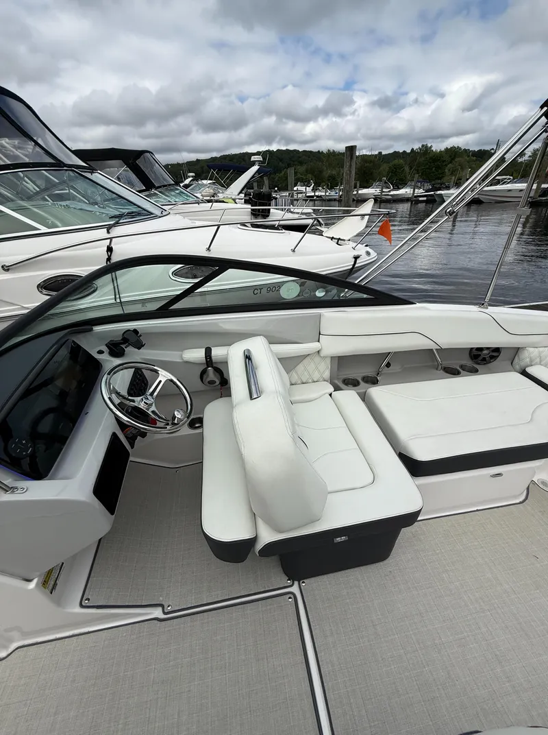 Slide: The Image of 2022 Regal LX2 boat interior with white seating and steering wheel at marina. - 15