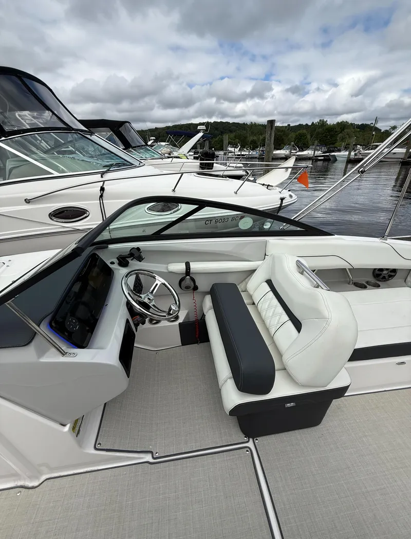 Slide: The Image of 2022 Regal LX2 boat interior with white seating and steering wheel at marina. - 17