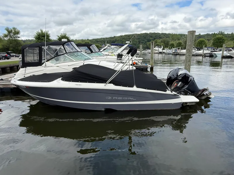 Slide: The Image of 2022 Regal LX2 boat docked on calm water, surrounded by other boats. - 2