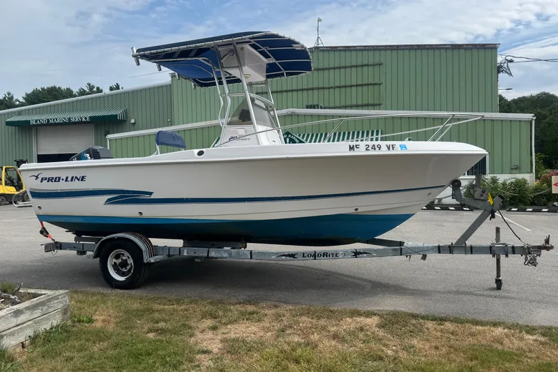 The Image of 2002 Pro-Line 20 Sport boat on trailer, parked outside marine service building. - 0