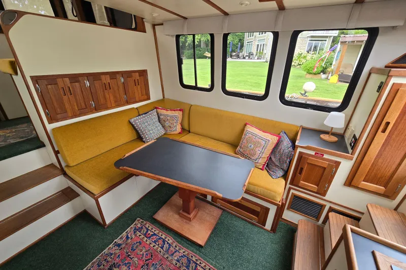 Slide: The Image of Cozy interior of 2001 Nordic Tug 32 with yellow seating, wooden accents, and large windows. - 14