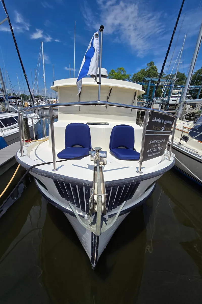 Slide: The Image of 2001 Nordic Tug 32 docked at marina, featuring blue seats and a flag. - 36