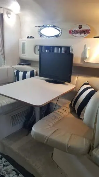 Slide: The Image of Interior of 1999 Sea Ray 270 boat with cozy seating, table, and TV. - 10