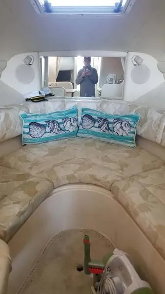 Slide: The Image of 1999 Sea Ray 270 cabin interior with nautical-themed pillows and a cozy seating area. - 7