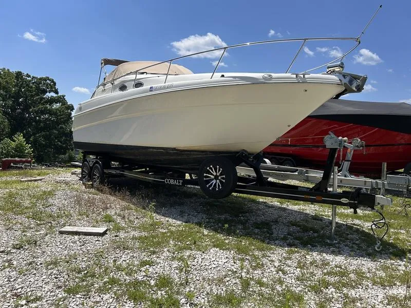 Slide: The Image of 1999 Sea Ray 270 boat on trailer, parked outdoors under clear blue sky. - 3