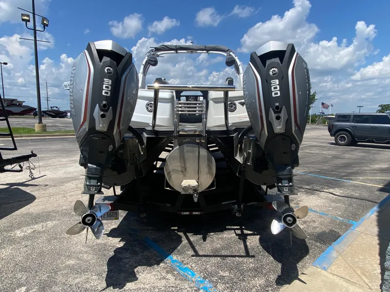 Slide: The Image of 2020 Manitou 25 Legacy SHP DL boat with dual 300 horsepower outboard engines in a parking lot. - 3