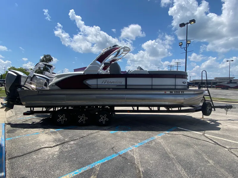 Slide: The Image of 2020 Manitou 25 Legacy SHP DL pontoon boat on trailer under blue sky. - 5