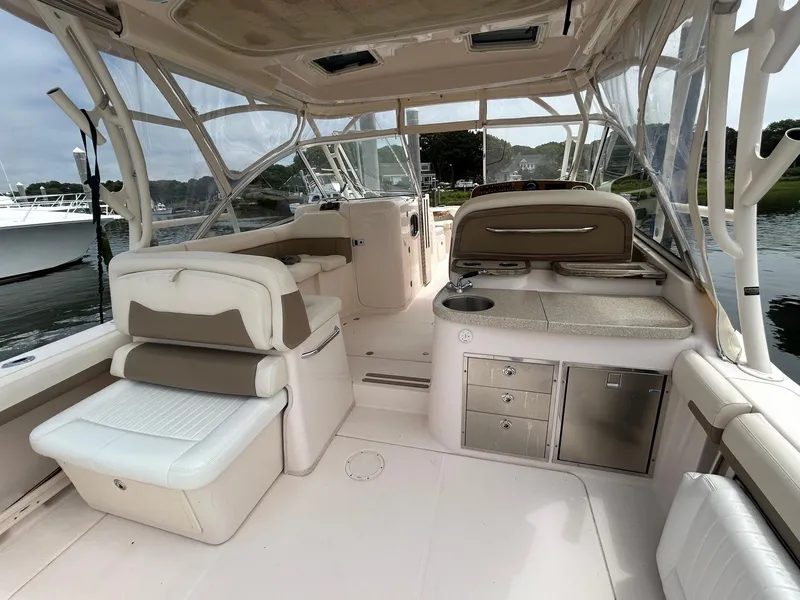 Slide: The Image of 2013 Grady-White Freedom 335 boat interior with cushioned seating and wooden table. - 12