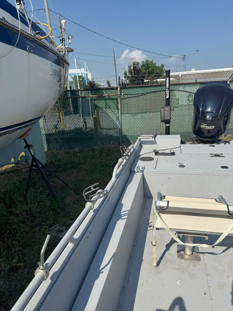 Slide: The Image of Boat docked with outboard motor, Sportsman 2400 G3, 2019 model, in a fenced area. - 3