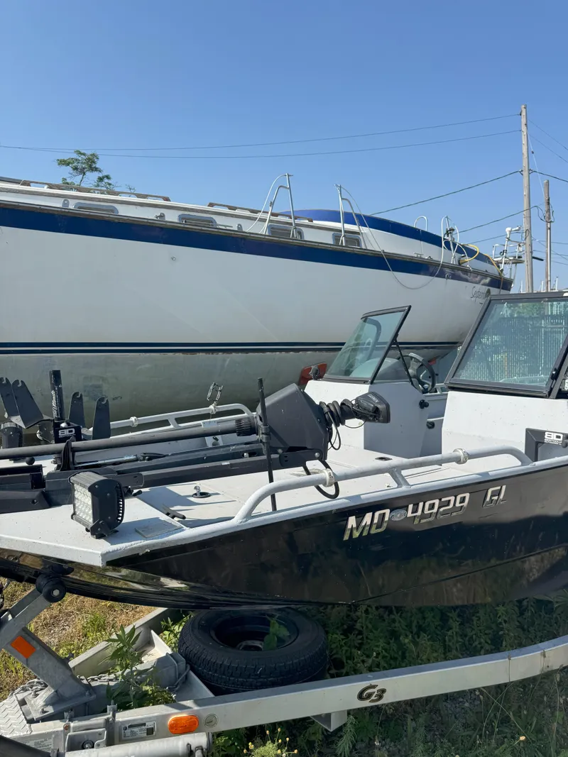 Slide: The Image of 2019 Sportsman 2400 G3 boat on trailer, parked beside a larger vessel. - 9
