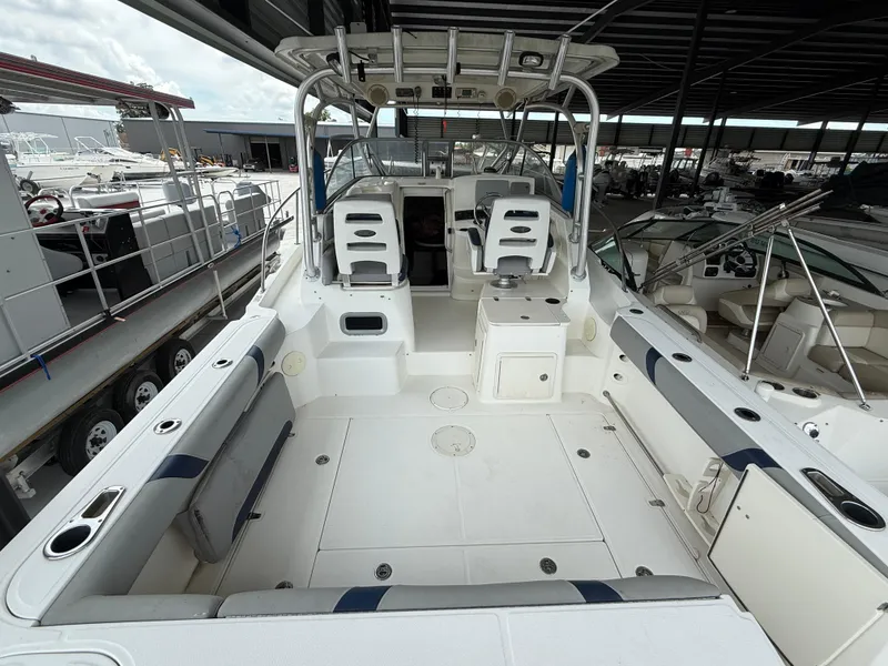 Slide: The Image of 2006 Boston Whaler 285 Conquest boat interior, spacious deck, seating, and helm under covered storage. - 10