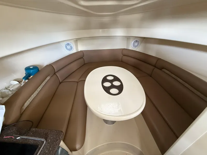 Slide: The Image of 2006 Boston Whaler 285 Conquest cabin interior with brown seating and oval table. - 15