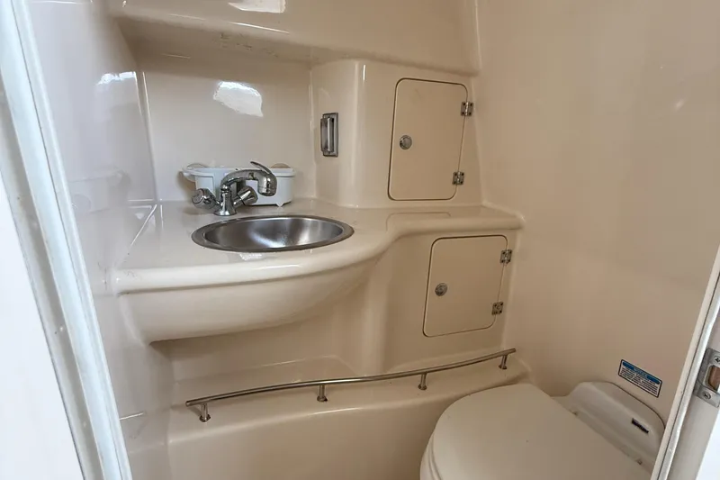 Slide: The Image of 2006 Boston Whaler 285 Conquest boat bathroom with sink, storage cabinets, and toilet. - 18