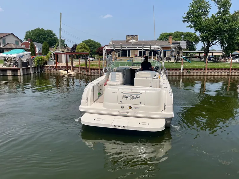 Slide: The Image of 2007 Sea Ray 290 Amberjack boat navigating a calm canal near residential area. - 2
