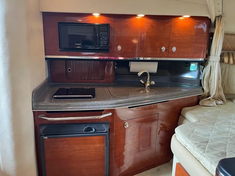 Slide: The Image of 2007 Sea Ray 290 Amberjack interior kitchen with microwave, sink, and wooden cabinetry. - 24
