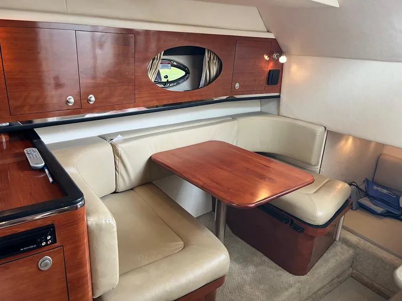 Slide: The Image of 2007 Sea Ray 290 Amberjack cabin interior with wood table and beige seating. - 28