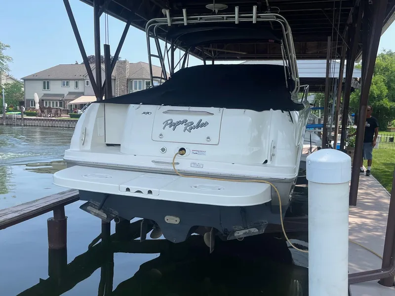 Slide: The Image of 2007 Sea Ray 290 Amberjack boat docked under a covered structure near waterfront homes. - 6