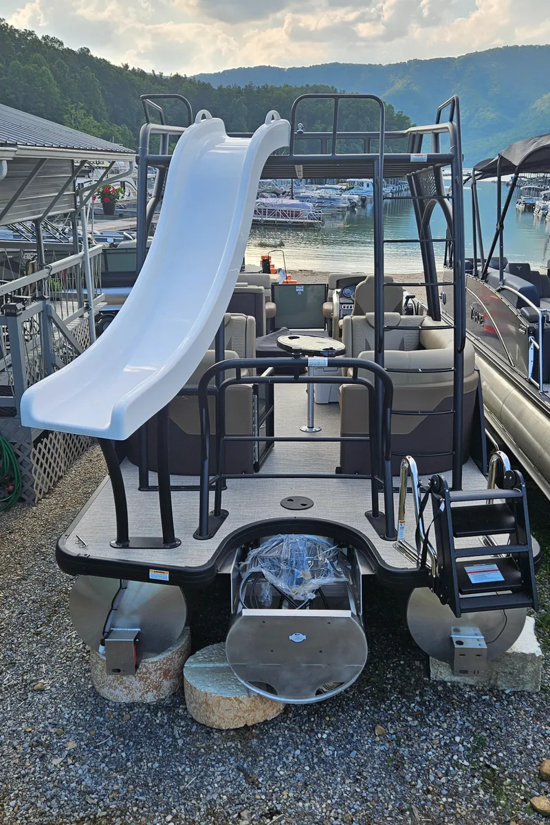 Slide: The Image of 2025 Godfrey MC255 SD pontoon boat with slide, docked by a scenic lake. - 4