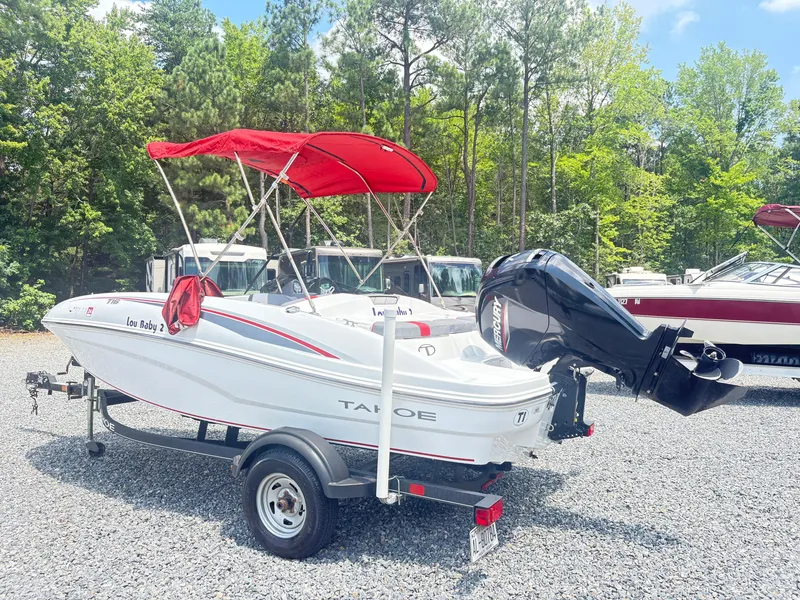 Slide: The Image of 2021 Tahoe T16 boat interior with seating, parked near RVs. - 10