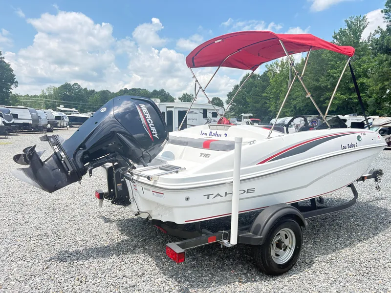 Slide: The Image of 2021 Tahoe T16 boat with red canopy, parked near RVs under a blue sky. - 11