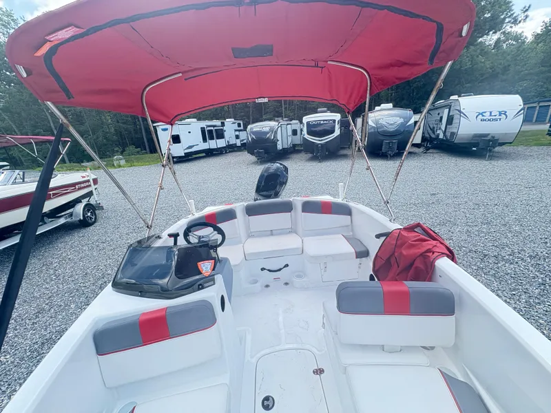 Slide: The Image of 2021 Tahoe T16 boat with red canopy on trailer, parked outdoors. - 2