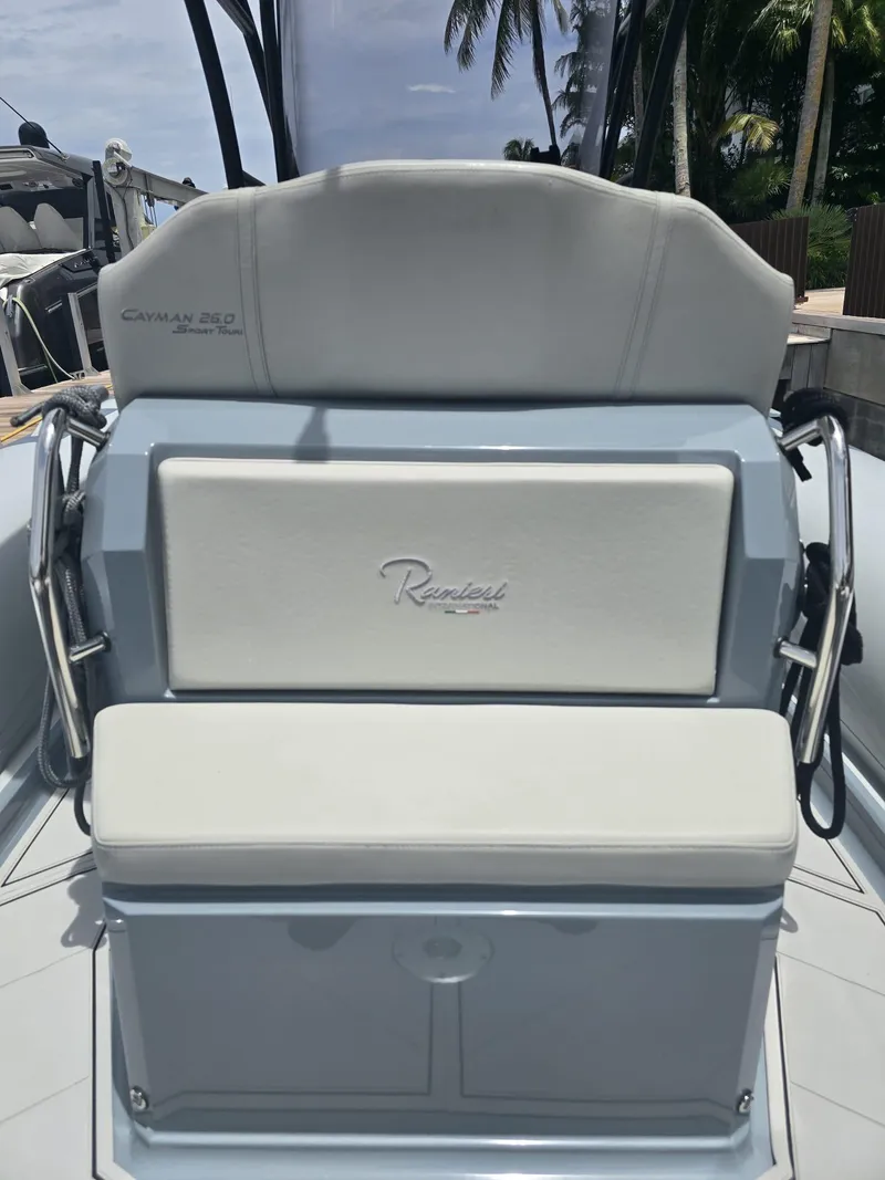 Slide: The Image of 2025 Ranieri CAYMAN 26 SPORT TOURING boat seat with logo, docked under palm trees. - 16