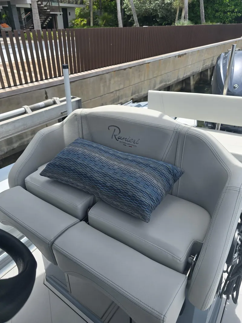 Slide: The Image of 2025 Ranieri CAYMAN 26 SPORT TOURING boat seat with blue cushion, dockside view. - 25