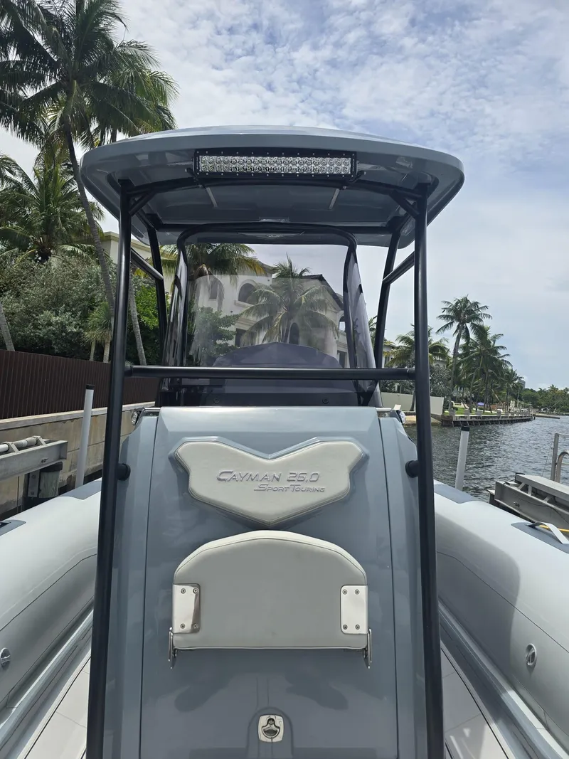Slide: The Image of 2025 Ranieri Cayman 26 Sport Touring boat docked, surrounded by palm trees and waterfront homes. - 31