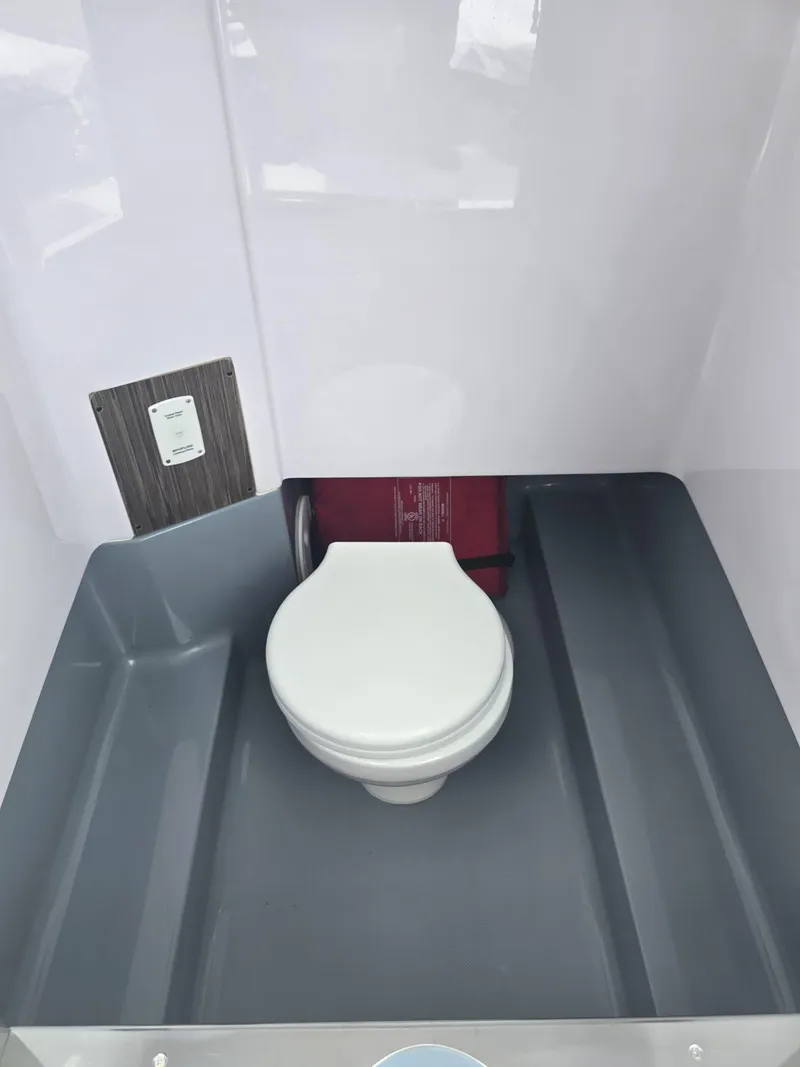Slide: The Image of Interior of 2025 Ranieri Cayman 26 Sport Touring boat, featuring a compact marine toilet. - 34