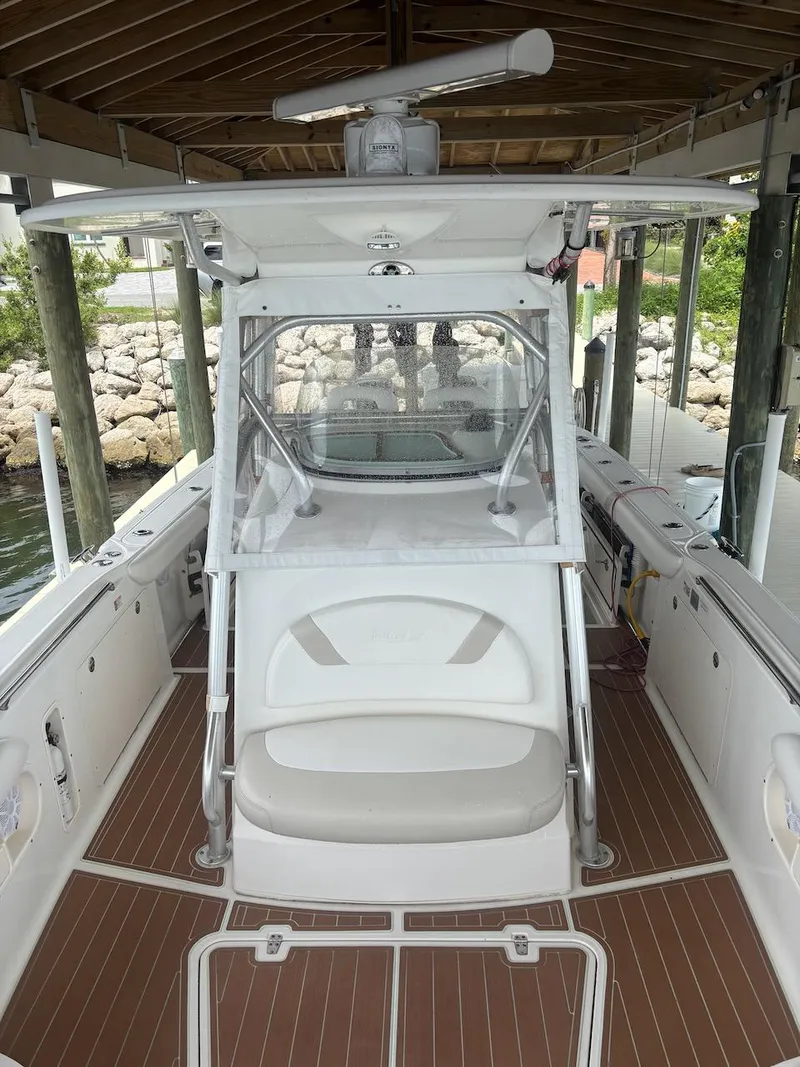 Slide: The Image of 2006 Boston Whaler 320 Outrage boat interior with seating and helm under a covered dock. - 12