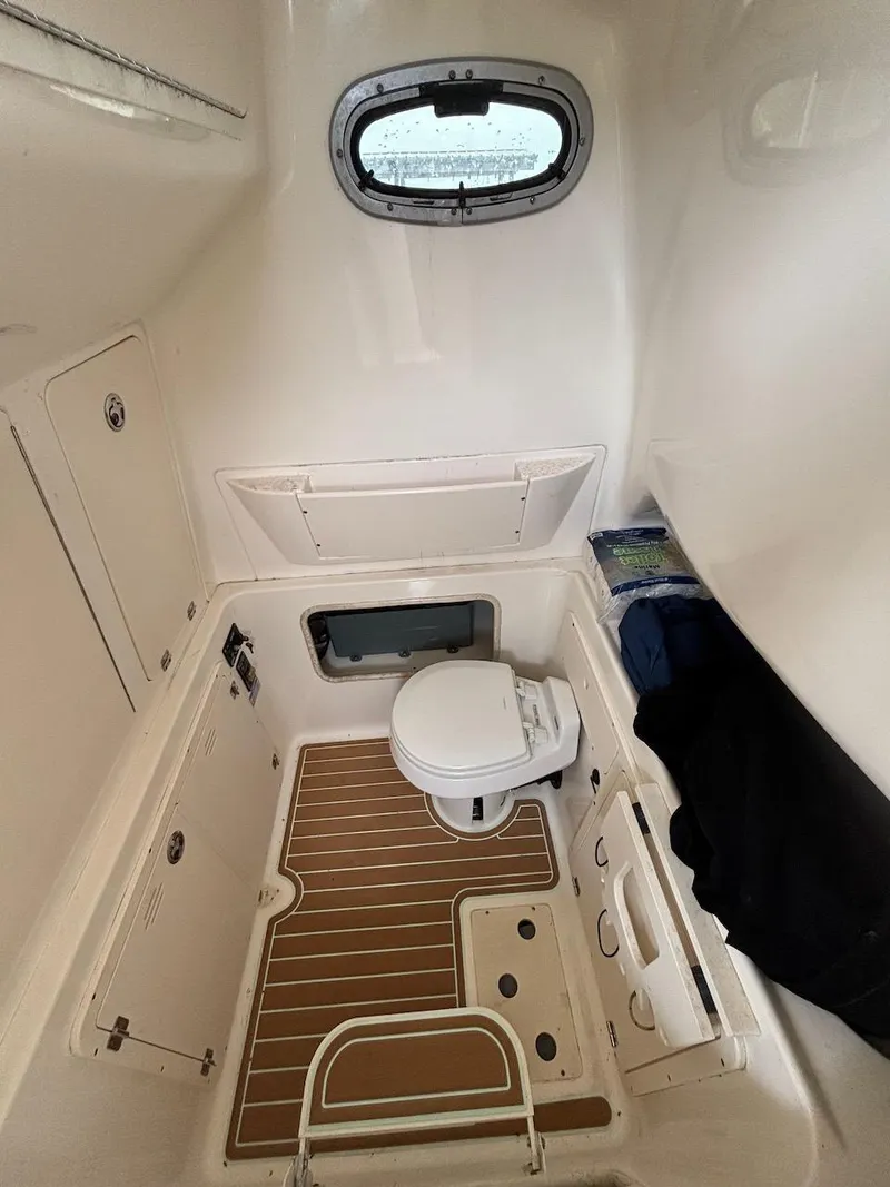 Slide: The Image of 2006 Boston Whaler 320 Outrage cabin interior with toilet and porthole window. - 13
