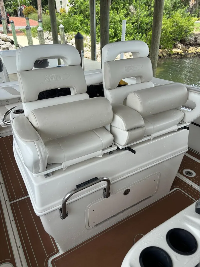 Slide: The Image of Luxury seating on a 2006 Boston Whaler 320 Outrage boat, docked near lush greenery. - 18