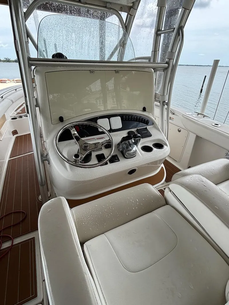 Slide: The Image of 2006 Boston Whaler 320 Outrage helm with steering wheel and controls, wet from rain. - 20