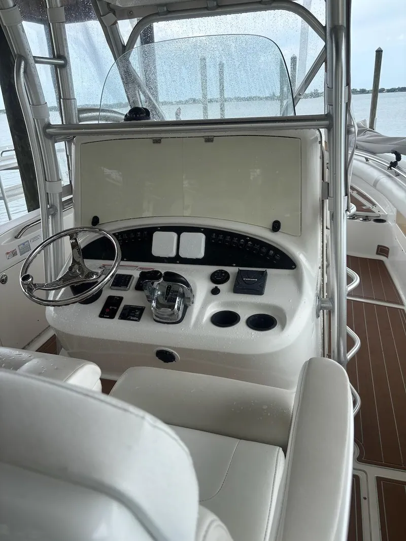 Slide: The Image of 2006 Boston Whaler 320 Outrage helm with steering wheel and controls, docked by the water. - 21
