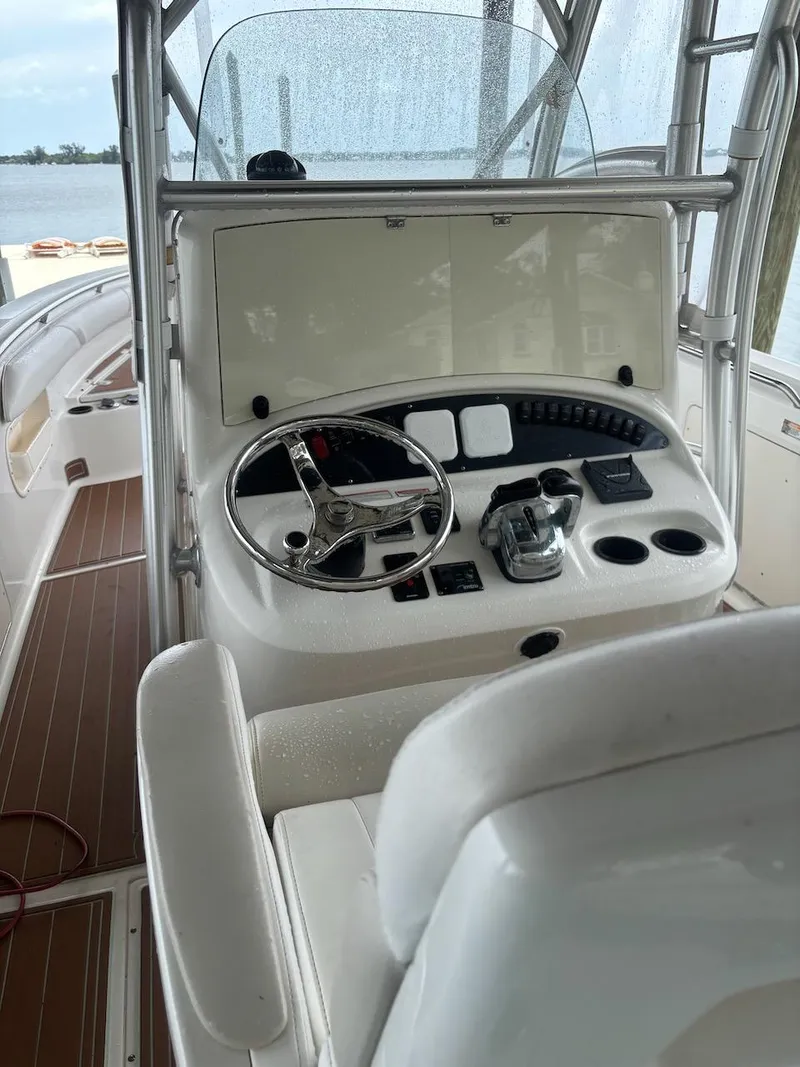 Slide: The Image of 2006 Boston Whaler 320 Outrage helm with steering wheel and controls, docked by the water. - 22