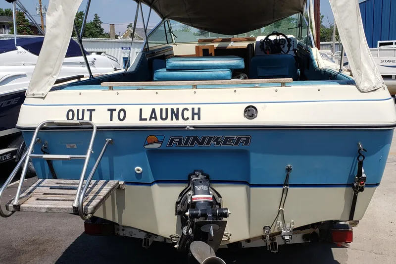Slide: The Image of 1984 Rinker V205 Cuddy Cabin boat, blue and white, with "Out to Launch" text on stern. - 1