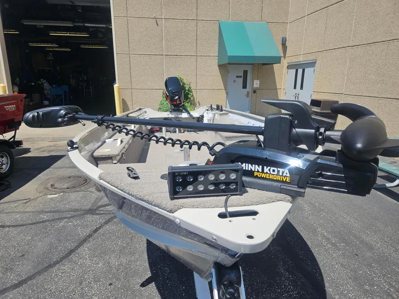 Slide: The Image of 2003 Sylvan 16SPTLTL boat with Minn Kota PowerDrive motor, parked outside a building. - 3