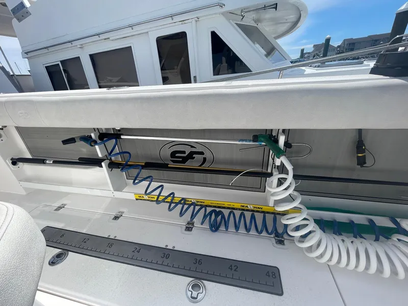 Slide: The Image of 2022 Sea Fox 368 Commander boat deck with fishing rod holders and coiled hoses. - 17