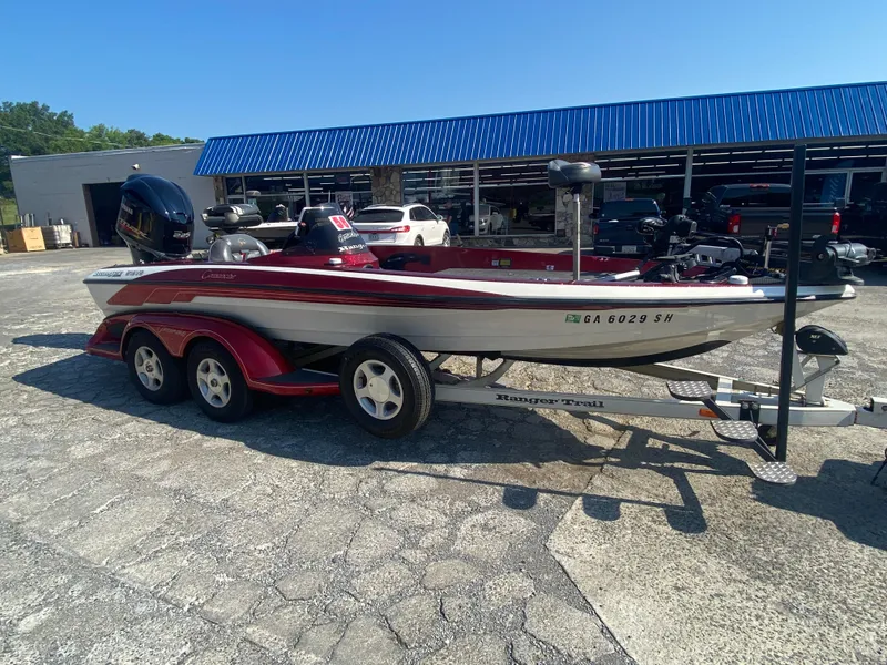 Slide: The Image of 1999 Ranger 519 VX/VS boat on trailer, parked outdoors near a blue-roofed building. - 6