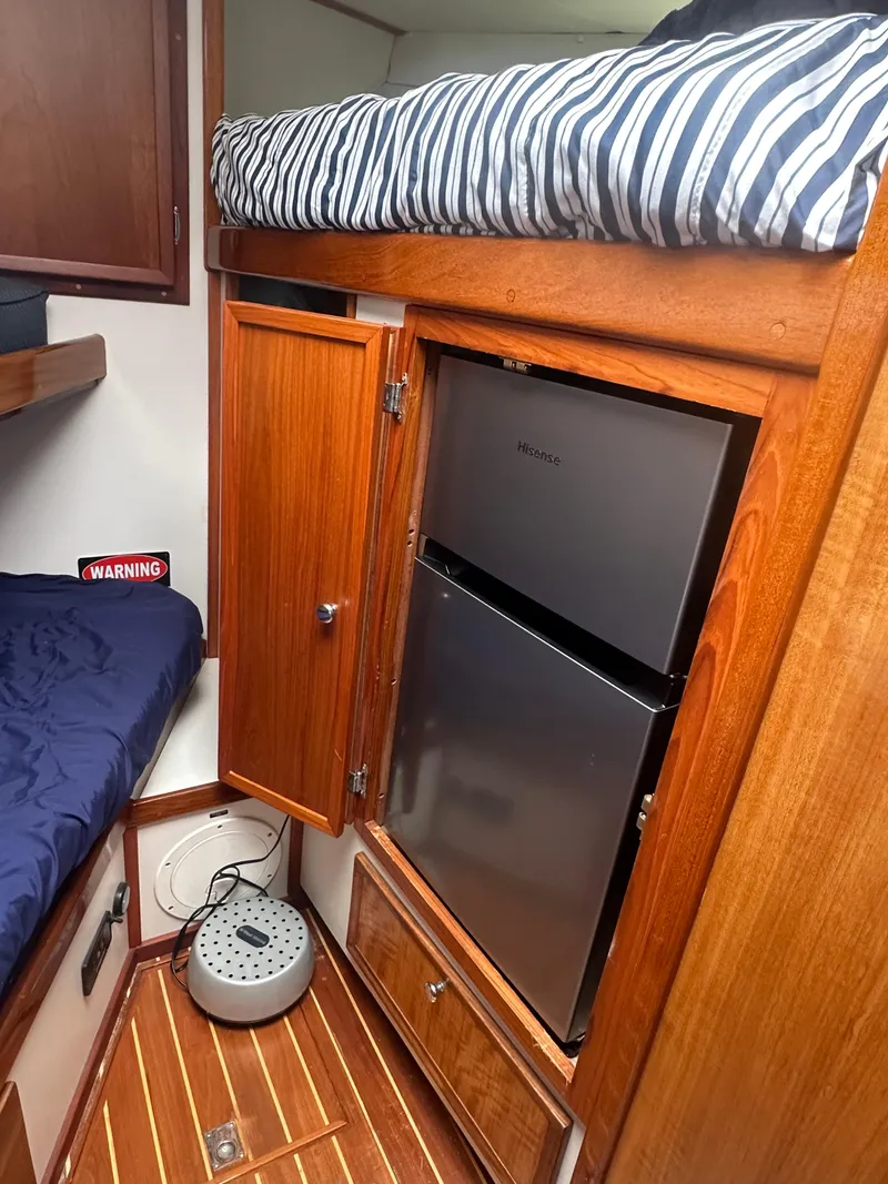 Slide: The Image of 1975 Hatteras Sport Fisher interior with bunk beds, wooden cabinetry, and compact refrigerator. - 19