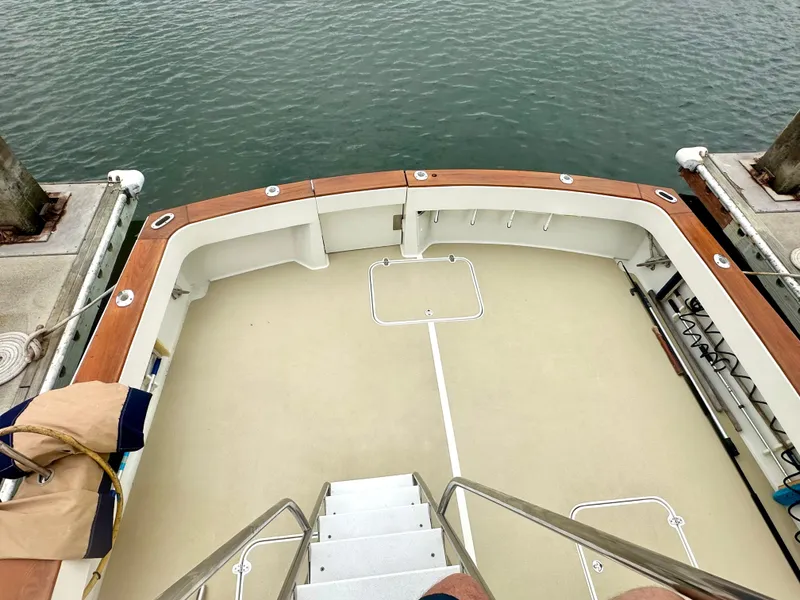 Slide: The Image of 1975 Hatteras Sport Fisher boat deck with wooden railings, docked by the water. - 35