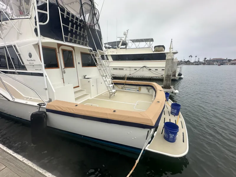 Slide: The Image of 1975 Hatteras Sport Fisher boat docked at marina, overcast sky, blue buckets on deck. - 43