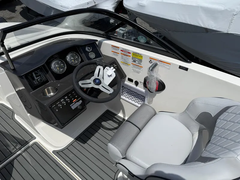 Slide: The Image of 2025 Bayliner VR5 Bowrider I/O cockpit with steering wheel, gauges, and cushioned seat. - 6