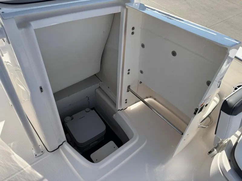 Slide: The Image of 2023 Robalo R202 Explorer boat interior with open storage compartment and portable toilet. - 17
