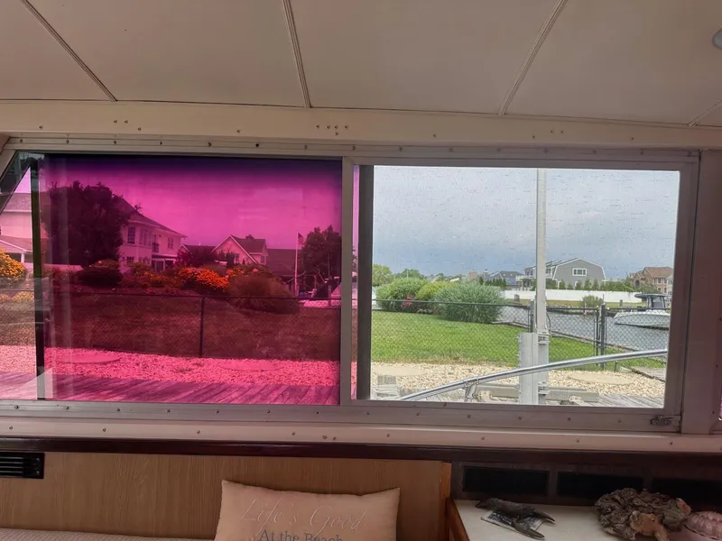 Slide: The Image of Interior view from a 1978 Bertram 33 Convertible boat, featuring tinted windows and waterfront scenery. - 14