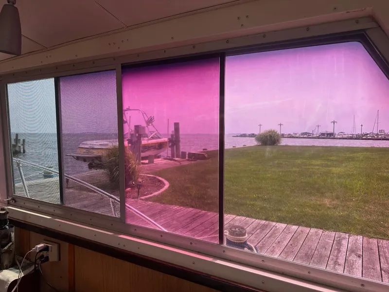 Slide: The Image of View from a 1978 Bertram 33 Convertible, overlooking a marina through tinted windows. - 15
