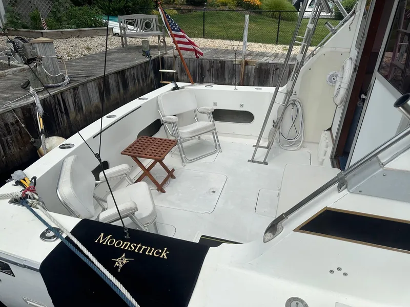Slide: The Image of 1978 Bertram 33 Convertible boat deck with chairs, table, and American flag. - 2